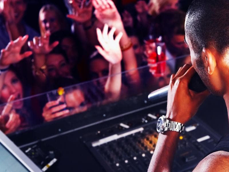 A DJ playing to a crowd of cheering students at a senior night party