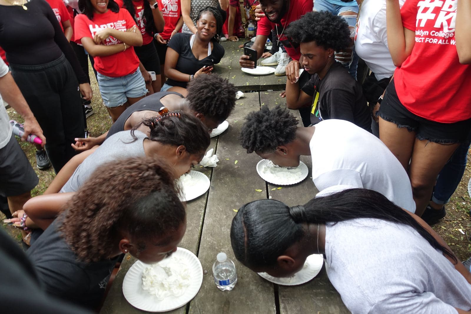 Students competing in a pie-eating contest at a picnic table